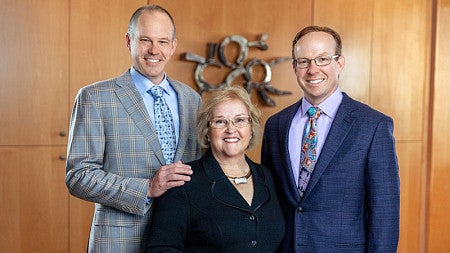 Susie Pape (seated, center) poses for a photo with her two sons, who are standing to her right and left sides