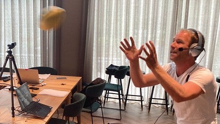 A man throws a football while broadcasting on Zoom