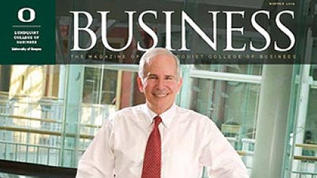 Cover image of magazine issue featuring a portrait of Dean Dennis Howard standing over a conference table full of papers and portfolios with his shirt sleeves rolled up, ready to get to work