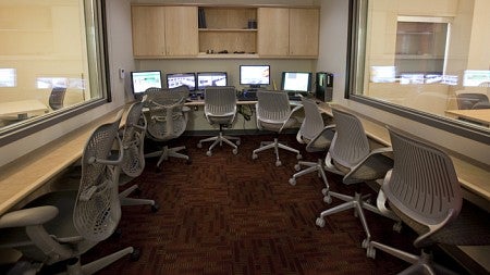 The inside of the control room showing five computer monitors and one-way glass looking out into adjoining rooms