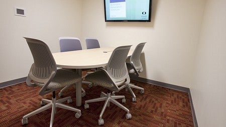 The inside of the small group room with a small conference table with 5 chairs and one TV screen on the wall