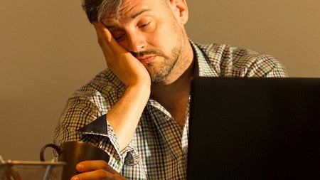 A tired man looks into a cup of coffee