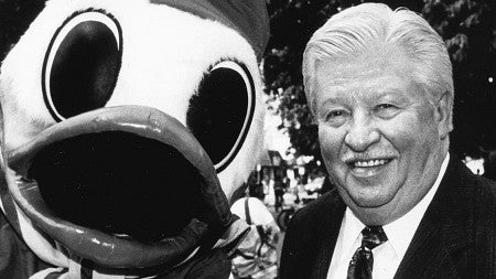 Charles Lundquist stands next to the Oregon Duck mascot in a black and white photo