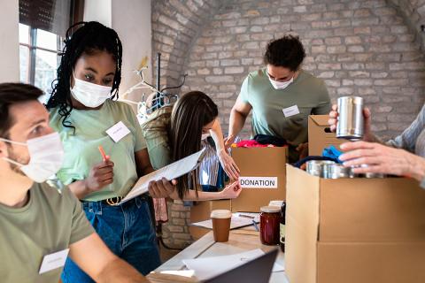 Masked volunteers boxing donated food and clothing.