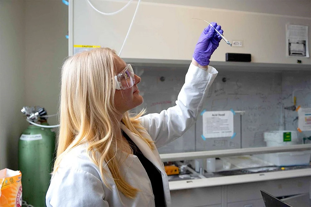 A lab technitian holding up a vial of solution