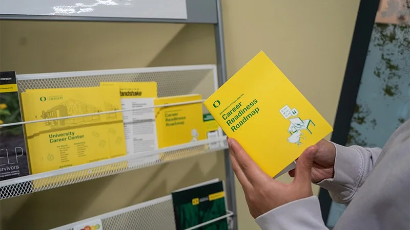 Person holding a yellow booklet with the title "Career Readiness Roadmap"