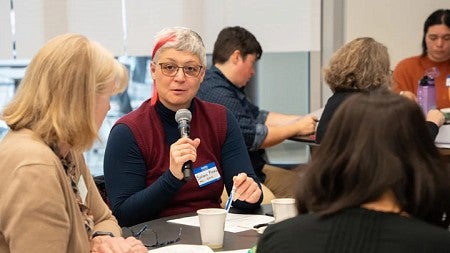 Person talking into a microphone seated at table