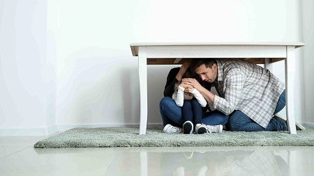 two people under a table during an earthquake