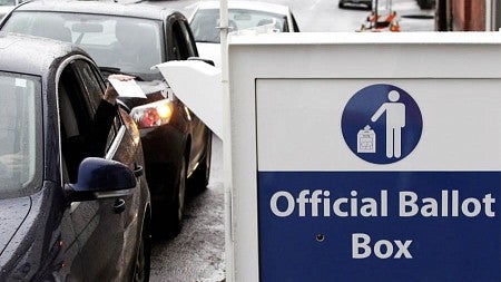 a person dropping a ballot in the mail