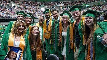a group of graduates in green cap and gowns