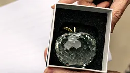 a person holds a crystal apple award