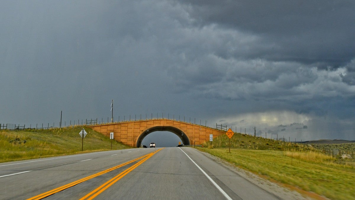 a bridge stands on the horizon with a dark gray sky overhead in Wyoming
