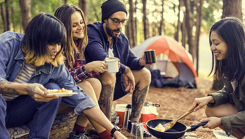 A group of friends cooks while camping