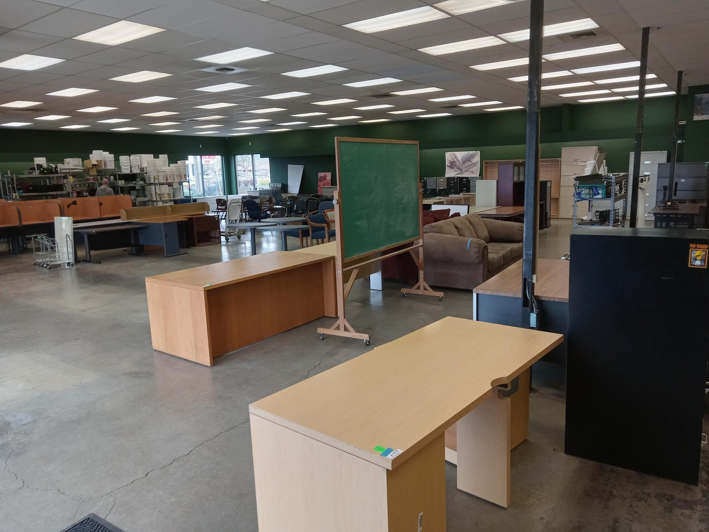 Interior of Surplus store with a rolling chalkboard, desks, chairs, and other furniture and shelving.