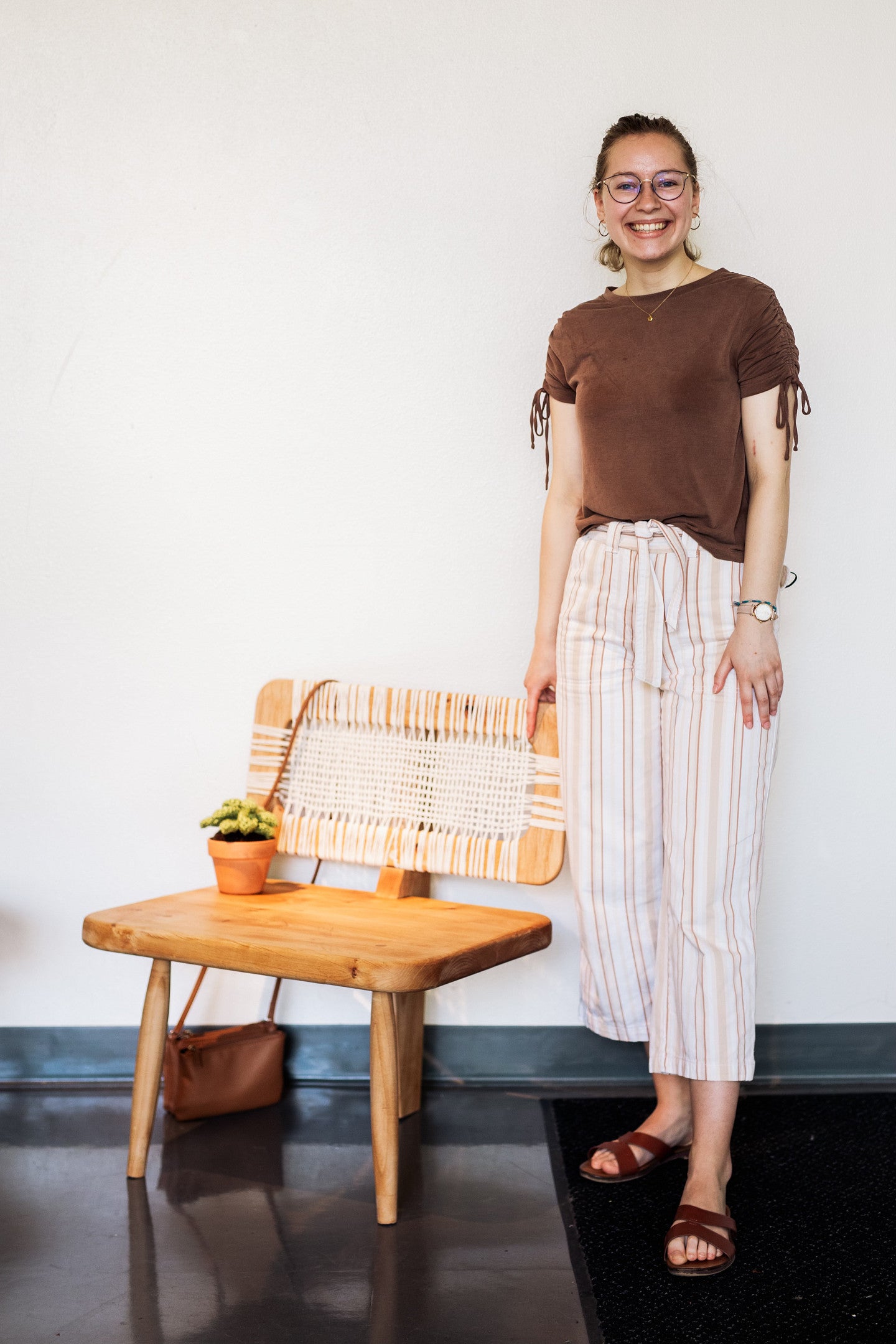 Alison standing with a 3-legged chair she designed for furniture studio.