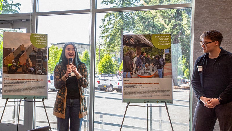 Two students present to the Tualatin community next to their project posters. 