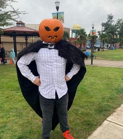 Photograph of Beny in Woodburn with a pumpkin on Beny's head and a cloak draped over shoulders.