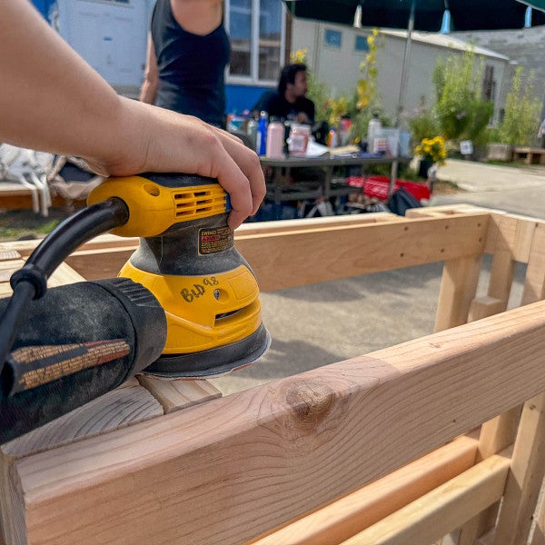 Student works on sanding a part of the wooden structure. 