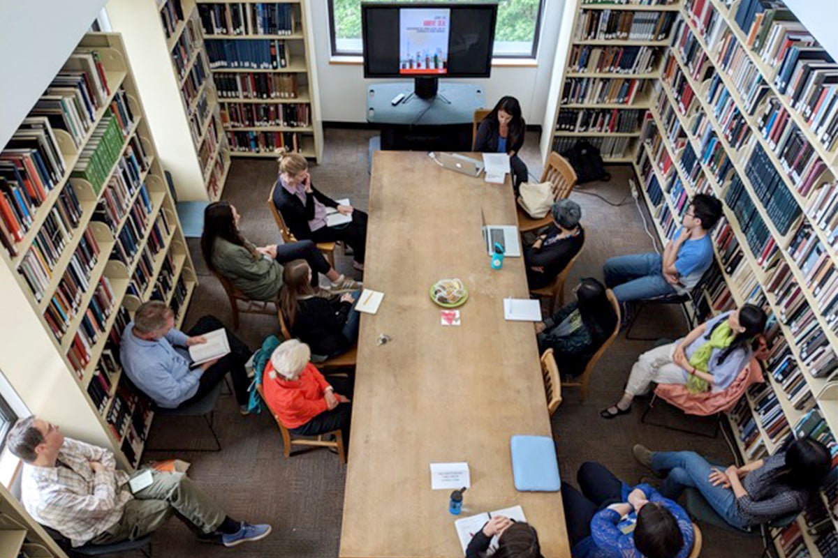 People sitting around a long table with books