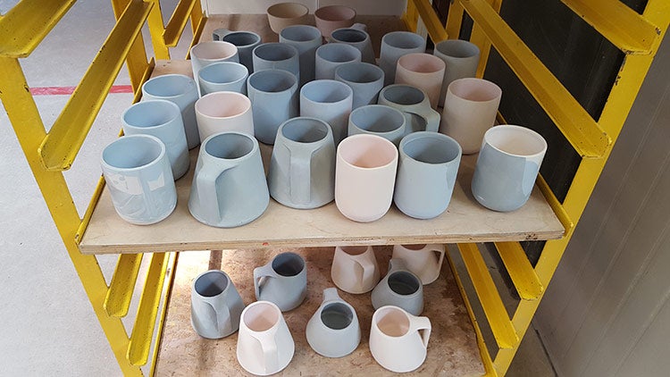 Cups on a cart await glazing and firing.