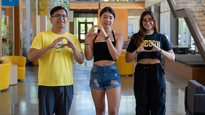 three UO international students making the Oregon O with their hands