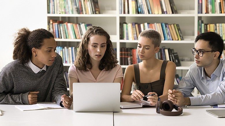 four individuals in a library sitting at a table