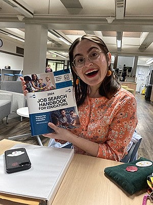 T. Acosta holding a job search handbook for educators
