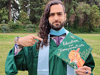 Santiago Navia in grad regalia pointing at cap