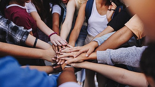 hands all piled together extended out layered on top of each other