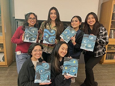 Grecia Acevedo and friends holding painted pictures