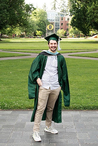 Alex Walker standing on UO campus with the UO O in the background