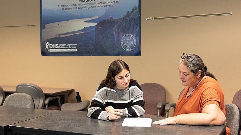 Student and community member sitting down at a table looking over a document