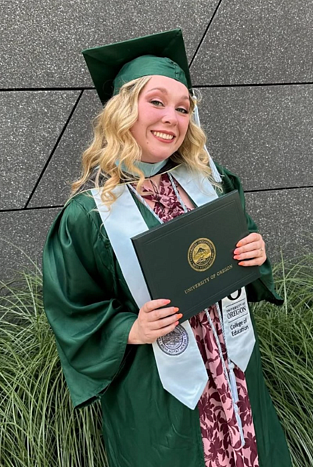 Emily Westlund in graduation regalia holding her College of Education degree