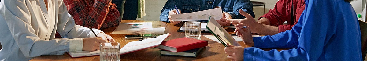 group of individuals sitting at a table with charts, graphs, and books on a table