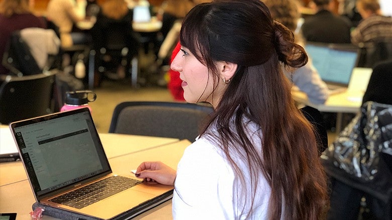 CDS students in class working on an open laptop