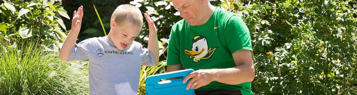 student working with a young child while holding a tablet