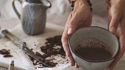 hands holding a cup of brown liquid