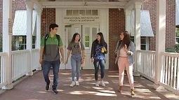 four students walking down walkway in front of EMPL doors