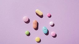 an assortment of pills laying on a pink background