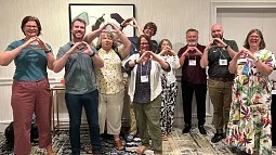 group of COE faculty past and present using their hands to form an O