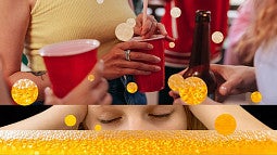 individuals holding red cups and a brown bottle