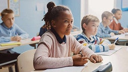 multiple children sitting in a classroom looking upwards