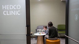individual with a child sitting at a table inside the HEDCO Clinic