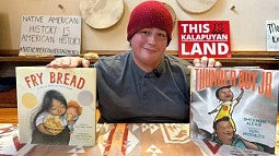 Sage Hatch holding up two books, Fry Bread and Thunder Boy Jr.