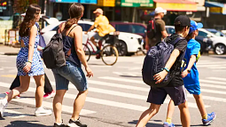 group of young individuals walking in the same direction, a few are wearing back packs