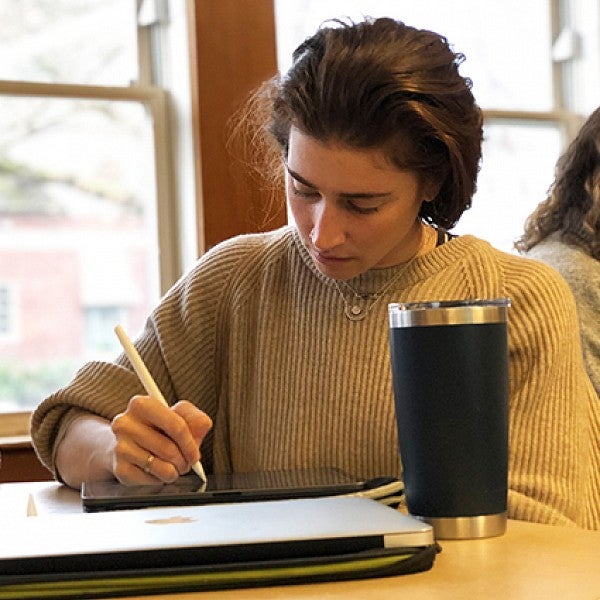 CDS student sitting in class writing on a tablet
