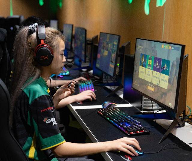 Student gaming with illuminated keyboard inside Esports Lounge.