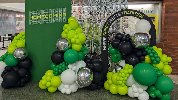 Homecoming display of green, yellow, white, and black balloons 