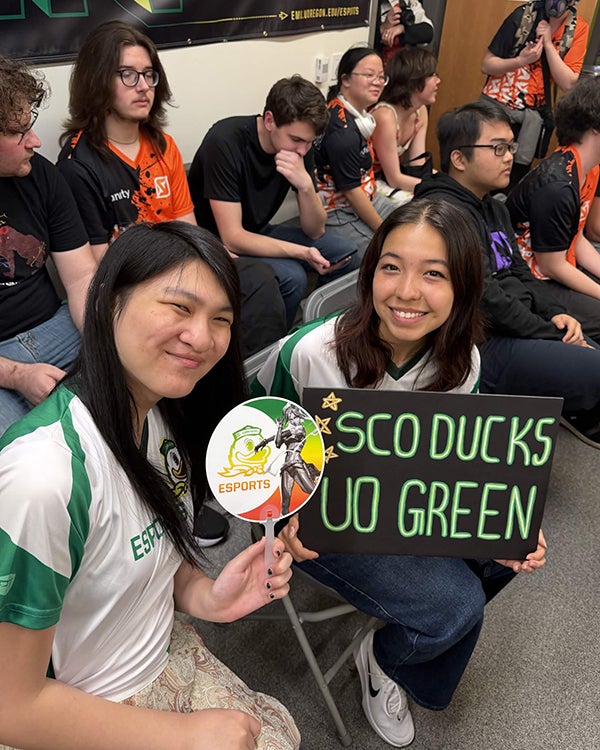 Two young women with black hair holding Go Ducks signs