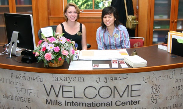 Student employees sitting at welcome desk at Mills International Center.